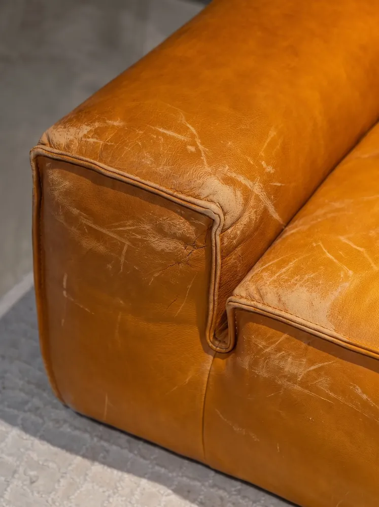 Dry, faded caramel leather two-seater before conditioning